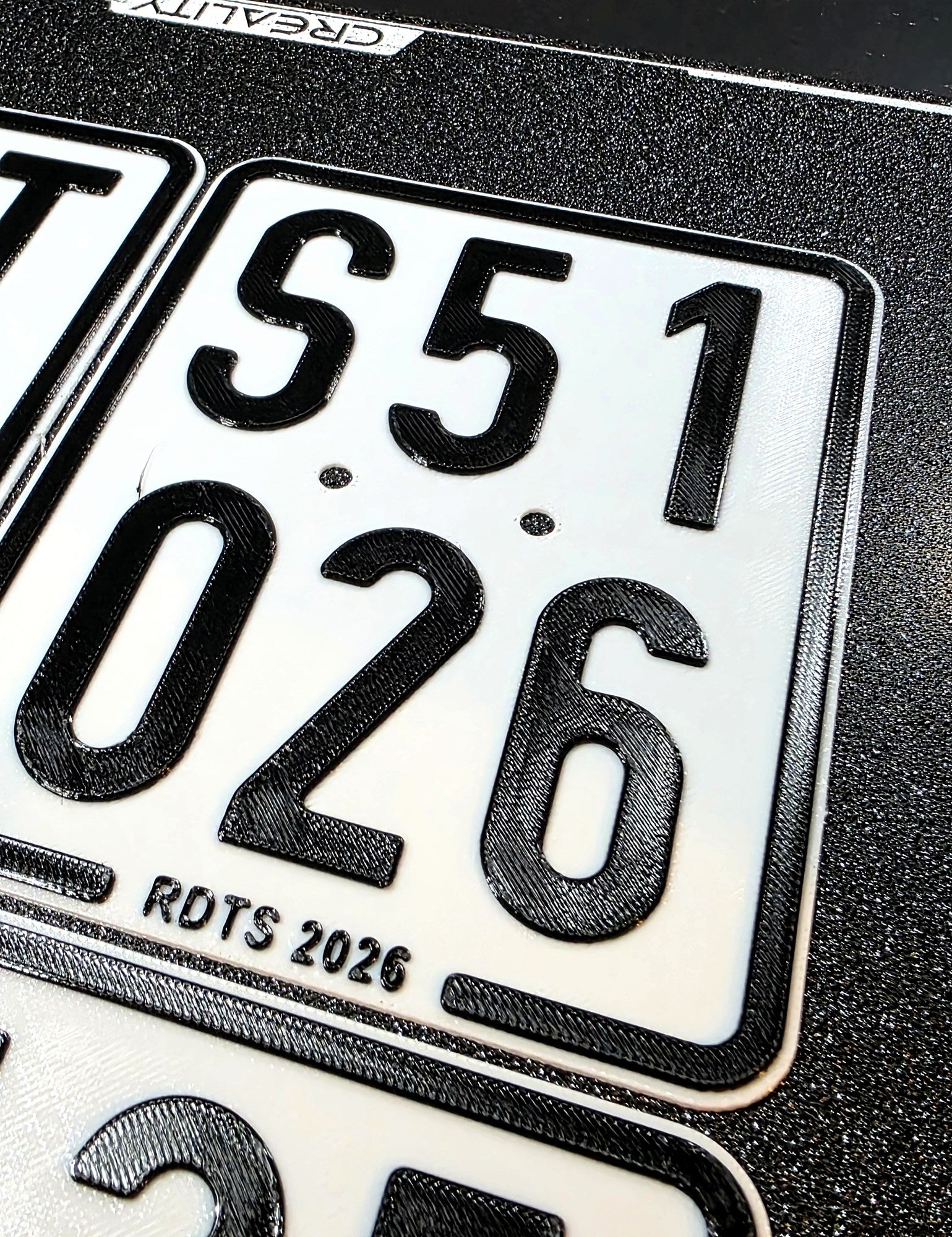 Moped-Kennzeichen schraeg fotografiert, erhabene Schrift wirft Schatten